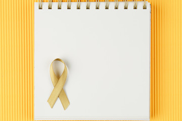 gold ribbon on open notebook isolated on yellow background