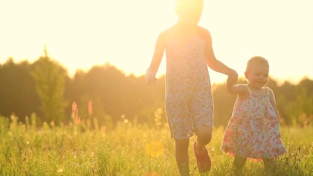 Happy Little Girls Playing together outdoor, on summer field. Playful kids, sisters outside, joy. Childhood concept. 4K UHD video Slow motion 240 fps, high speed camera 