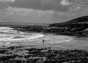 Surfer returns from the sea. Greyscale image with moody sky