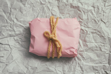 Soft pouch wrapped in craft paper and tie cord. Crumpled paper background texture. Delivery service. Online shopping. 