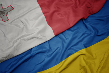 waving colorful flag of ukraine and national flag of malta.