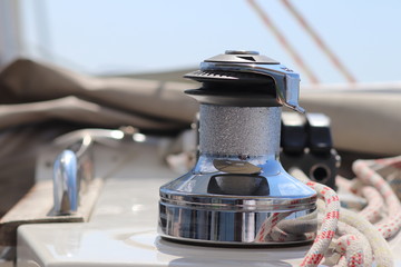 A winch on a sailing yacht for pulling up files and sheets against the background of the summer sea. Outfit of a sailing yacht. Facilitating human labor on board. Mar practice in a yachting school.