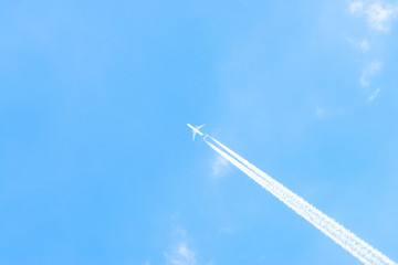 Airplane in a blue sky with clouds and condensation trails, Germany
