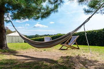 Hammock hangs from 2 trees with deckchairs