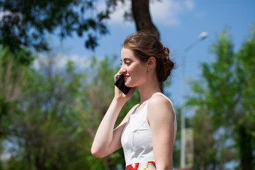 Portrait of happy young brunette woman in dress talking on the phone