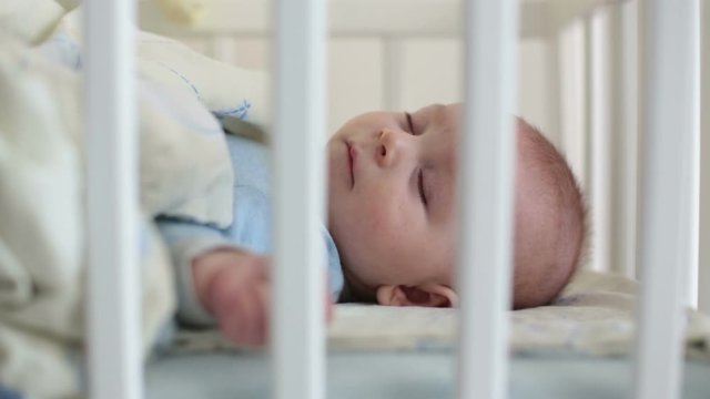 Close up of a little baby boy sleeping, baby lying in baby cot