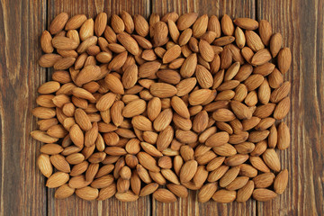 Top view of a pile of peeled raw almonds lying on a brown wooden table