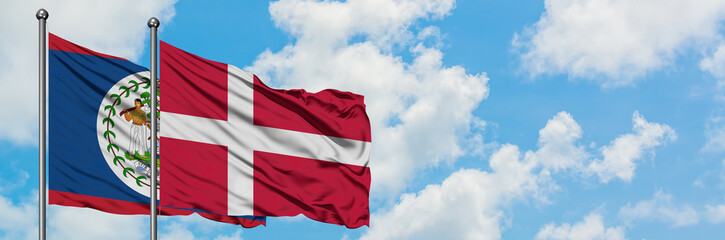Belize and Denmark flag waving in the wind against white cloudy blue sky together. Diplomacy concept, international relations.