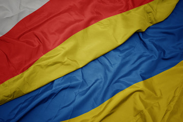 waving colorful flag of ukraine and national flag of south ossetia.
