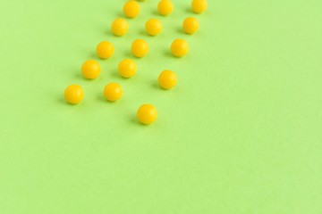 Row of yellow pills for health care with selective focus on neon green background. Pharmacology supplements on green backdrop with empty space for text. Medicine pills. Vitamins