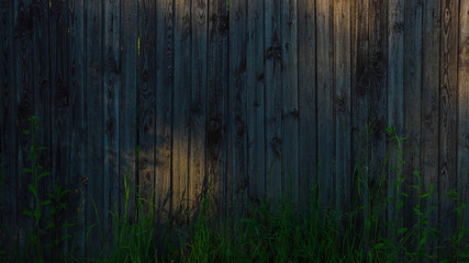 Old wooden fence in the countryside in the rays of the setting sun