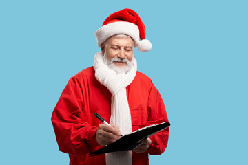Santa Claus writing down in clipboard children's wishes