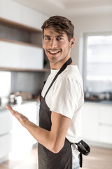 in full growth. attractive young man standing in home kitchen