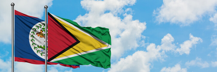 Belize and Guyana flag waving in the wind against white cloudy blue sky together. Diplomacy concept, international relations.
