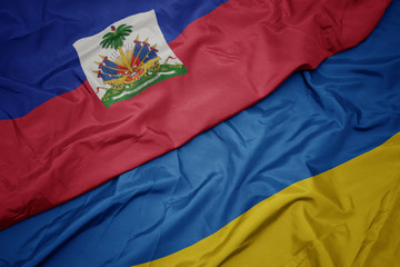 waving colorful flag of ukraine and national flag of haiti.
