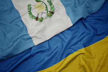 waving colorful flag of ukraine and national flag of guatemala.