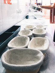 detail of baker's hand pouring a little flour with a sieve on bread baskets