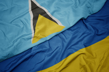 waving colorful flag of ukraine and national flag of saint lucia.
