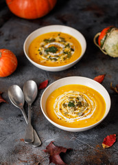 Vegetarian autumn pumpkin cream soup with seeds in white bowls. Pumpkin soup