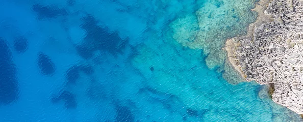 Foto auf Acrylglas Eine Luftaufnahme des wunderschönen Mittelmeers, wo Sie die felsigen Unterwasserkorallen und das saubere türkisfarbene Wasser der blauen Lagune Agia Napa sehen können © Valentinos Loucaides