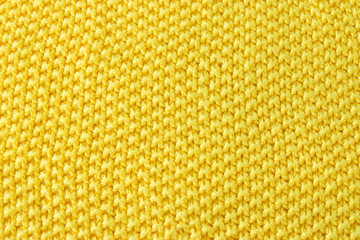 Knitted fabric textured background. Texture of a yellow knitted sweater.