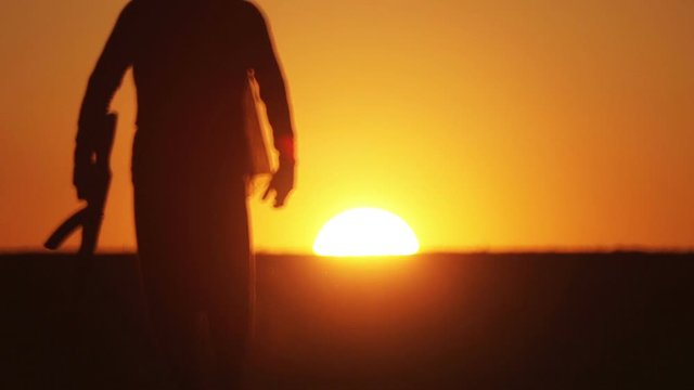 warrior with Kalashnikov at sunset day. fighter is training with a machine gun at sunset.