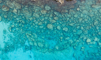 An aerial view of the beautiful Mediterranean sea, where you can se the rocky textured underwater corals and the clean turquoise water of blue lagoon Agia Napa