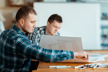 An engineer picking up a pen to correct.