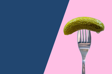 Pickle on fork, dill, gherkin, blue and pink background, national pickle day	