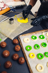 pastry chef decorates raw profiteroles with green and yellow shortcrust pastry.