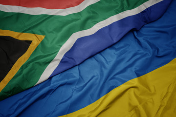 waving colorful flag of ukraine and national flag of south africa.