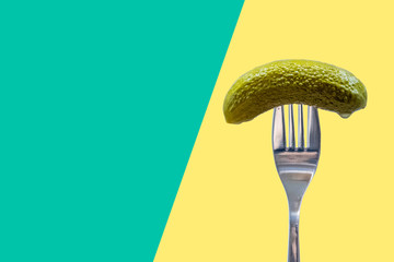 Pickle on fork, dill, gherkin, green and yellow background, national pickle day	