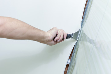 Process of installing stretch ceiling in the bathroom. Close up of the hand of man with a tool.