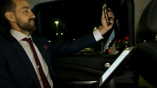 Happy businessman dacing in the back seat of his limousine at night
