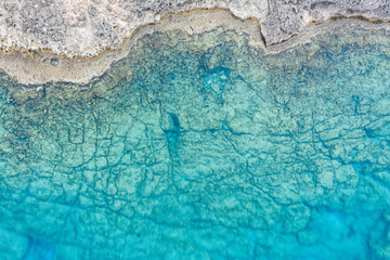 An aerial view of the beautiful Mediterranean sea, where you can se the rocky textured underwater corals and the clean turquoise water of blue lagoon Agia Napa