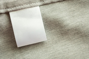 White blank laundry care clothing label on gray fabric texture background