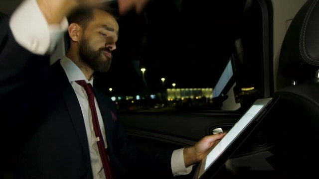 Excited businessman in suit dacing in the back seat of his limousine