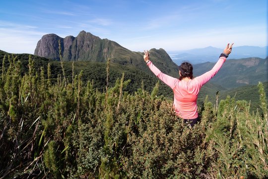 Mulher montanhista contemplando a paisagem e comemorando