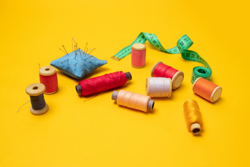 Accessories and tools for sewing on a yellow background. Top view, flat lay. Copy space for text.