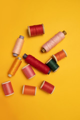 Multi-colored thread spools on a yellow background.