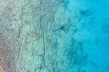 An aerial view of the beautiful Mediterranean sea, where you can se the rocky textured underwater corals and the clean turquoise water of blue lagoon Agia Napa
