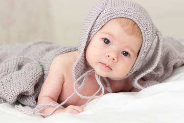 Little Caucasian baby baby 3 months in a gray knitted hat. Portrait of a small child, close-up soft focus