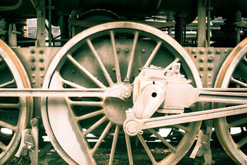 Industrial or transportation or steam punk vintage background with detail of old rusty steam locomotive featuring crank mechanism, frame and  wheels. 