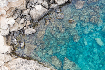 An aerial view of the beautiful Mediterranean sea, where you can se the rocky textured underwater corals and the clean turquoise water of blue lagoon Agia Napa