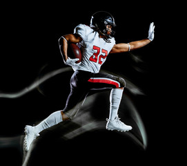 Fototapeta na wymiar one african american football player man studio shot isolated on black background with light painting with blurred motion speed effect