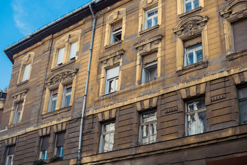 Fototapeta na wymiar History or architecture background featuring details of gloomy dark facades of historical vintage buildings waiting renovation in downtown Budapest, Hungary. 