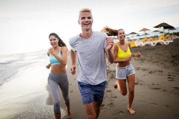 Group of athletes running on ocean front. Friends in sportswear training together outdoors.