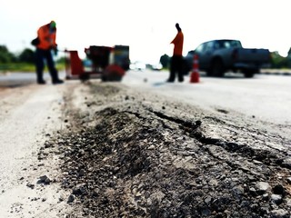 The paved road is damaged. And there are workers fixing the road