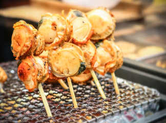 Delicious grilled scallop street food at Kuromon Ichiba Market, Osaka