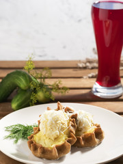 Karelian Pirakka pies located on a white plate. Nearby is fermented beet juice and fresh cucumbers. Traditional dish of Karelia and Finland from rye flour with different fillings. Close-up